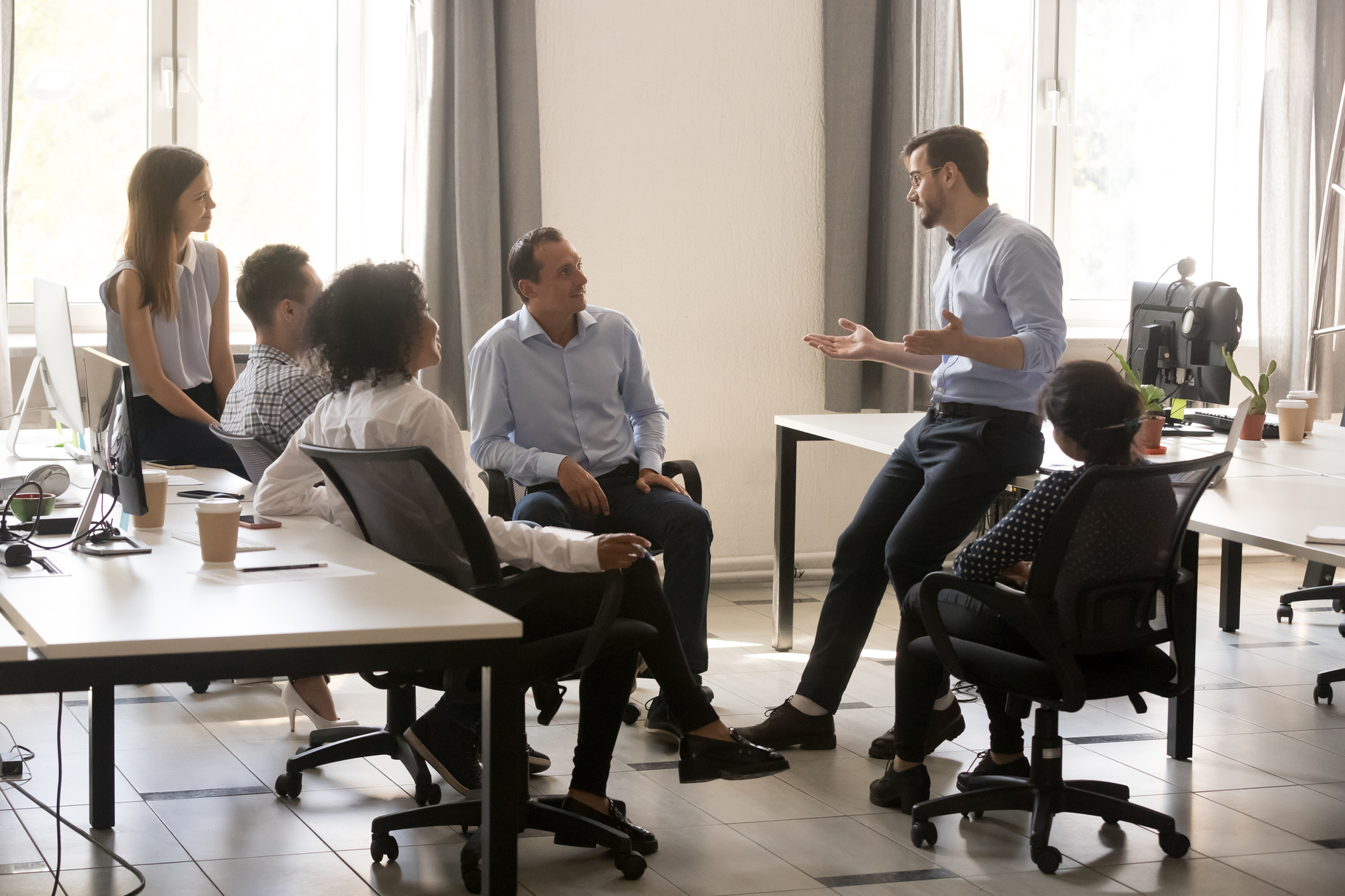 Male team leader talking to diverse businesspeople at office meeting